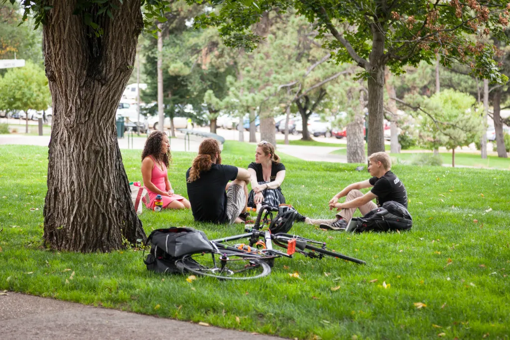 faculty and staff sitting on main hall lawn with bikes in grass